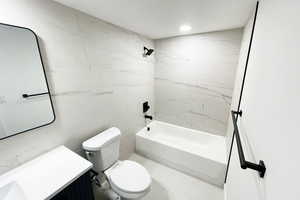 Full bathroom featuring tile walls, toilet, vanity, and tiled shower / bath