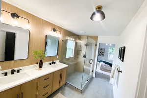 Bathroom with a shower with door, double sink vanity, and tile patterned flooring