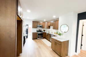 Kitchen with light hardwood / wood-style floors, appliances with stainless steel finishes, and sink