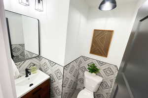 Bathroom featuring vanity, tile walls, and toilet