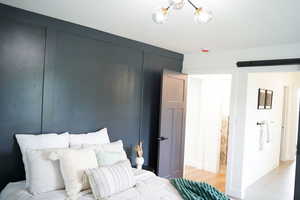 Bedroom with light hardwood / wood-style floors and a barn door