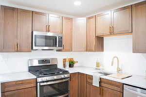 Kitchen featuring tasteful backsplash, appliances with stainless steel finishes, and sink