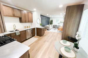 Kitchen with dishwasher, light hardwood / wood-style floors, decorative backsplash, gas cooktop, and sink