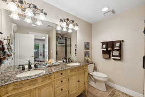 Bathroom featuring tile patterned flooring, dual vanity, french doors, and toilet