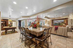 Dining area with light tile patterned flooring, a raised ceiling, billiards, and a textured ceiling