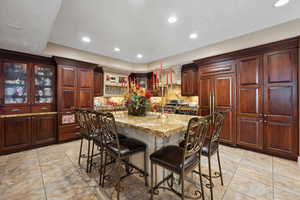 Kitchen featuring light tile patterned flooring, tasteful backsplash, paneled fridge, a center island, and a kitchen bar