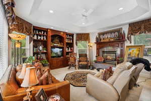 Tiled living room featuring a premium fireplace, a wealth of natural light, and a tray ceiling