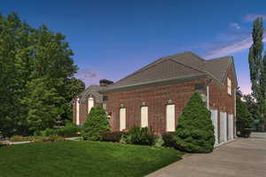 Property exterior at dusk with a garage and a lawn