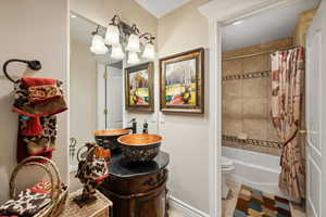 Full bathroom with tile patterned floors, vanity, shower / bath combo with shower curtain, and toilet