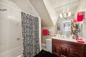 Bathroom featuring tile patterned floors, vanity, vaulted ceiling, and shower / tub combo with curtain