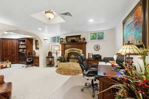 Carpeted home office with a fireplace