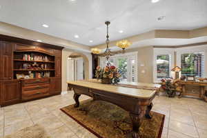 Game room featuring a notable chandelier, french doors, light tile patterned floors, and a textured ceiling