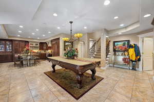 Playroom with a notable chandelier, light tile patterned floors, and a tray ceiling