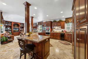 Kitchen featuring a kitchen bar, decorative columns, a wealth of natural light, and light tile patterned floors