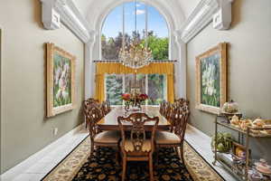 Dining space featuring a notable chandelier, tile patterned floors, and a towering ceiling