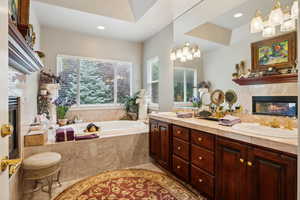 Bathroom featuring tiled bath, tile patterned floors, and dual bowl vanity