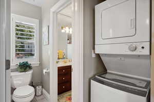 Laundry room with stacked washer and dryer and light tile patterned floors