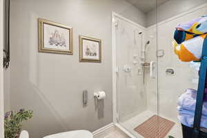 Bathroom featuring a shower with shower door, toilet, and tile patterned floors