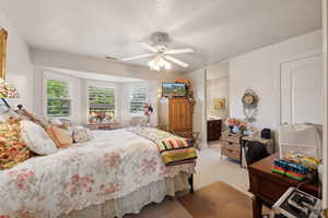 Bedroom with ensuite bathroom, a textured ceiling, ceiling fan, and carpet flooring