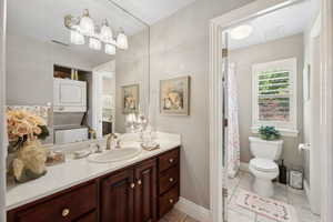 Bathroom with tile patterned flooring, stacked washer / dryer, toilet, and vanity