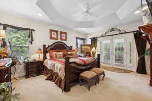 Carpeted bedroom with ceiling fan, french doors, access to exterior, and a tray ceiling