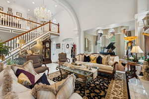 Living room featuring an inviting chandelier, high vaulted ceiling, and tile patterned floors