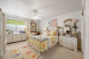 Carpeted bedroom featuring a textured ceiling and ceiling fan