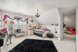 Carpeted bedroom with an inviting chandelier, a textured ceiling, and lofted ceiling