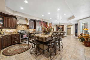 Kitchen with a kitchen breakfast bar, tasteful backsplash, light tile patterned floors, and range with two ovens