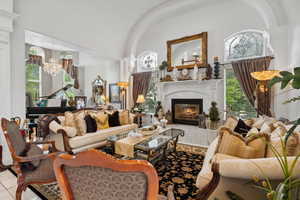 Living room featuring an inviting chandelier, a fireplace, tile patterned flooring, and a towering ceiling