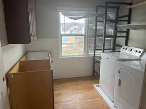 Washroom featuring cabinets, washer and clothes dryer, and light wood-type flooring