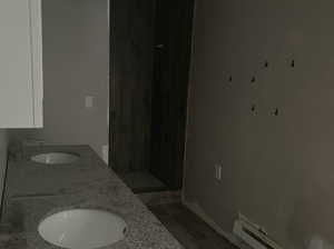 Bathroom featuring hardwood / wood-style flooring, baseboard heating (not currently working), and double sink vanity