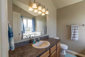 Bathroom featuring tile patterned floors, vanity, lofted ceiling, and toilet