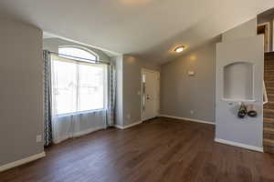 Empty room with lofted ceiling and dark hardwood / wood-style flooring