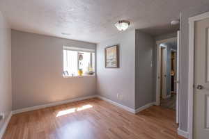 Unfurnished room with light wood-type flooring and a textured ceiling