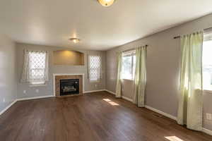 Unfurnished living room with dark wood-type flooring and a fireplace