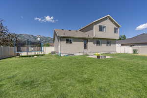 Back of house featuring a mountain view, a trampoline, and a yard