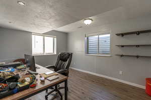 Office area with a textured ceiling and dark hardwood / wood-style floors