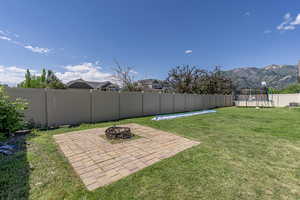 View of yard featuring a mountain view, a patio area, a trampoline, and a fire pit