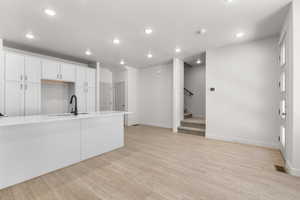 Kitchen with sink, light hardwood / wood-style flooring, and white cabinetry