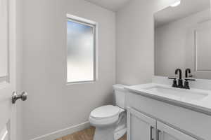 Bathroom featuring vanity, hardwood / wood-style flooring, toilet, and a wealth of natural light