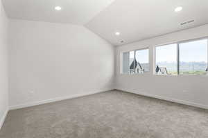 Spare room featuring carpet flooring and vaulted ceiling