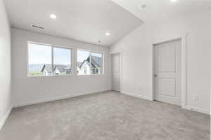 Carpeted empty room featuring lofted ceiling and plenty of natural light