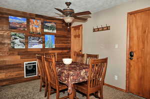 Dining room with a textured ceiling, carpet floors, and ceiling fan