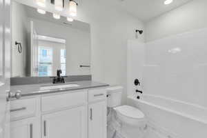 Full bathroom featuring vanity, tiled shower / bath combo, toilet, and tile patterned floors