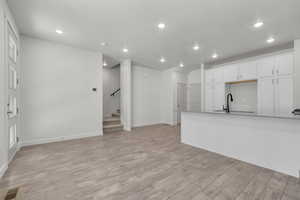 Unfurnished living room with sink, a textured ceiling, and light hardwood / wood-style flooring