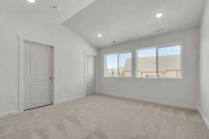 Unfurnished bedroom featuring lofted ceiling, light carpet, and a textured ceiling