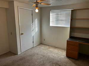 Unfurnished bedroom with ceiling fan, light carpet, and a textured ceiling