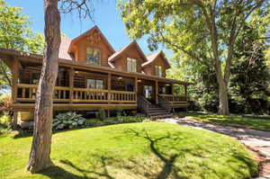 Front of Log home with a front lawn and large covered porch