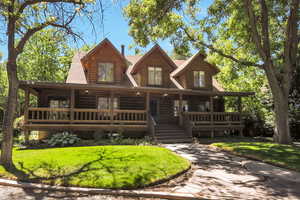 Front of Log home with a front lawn and large covered porch